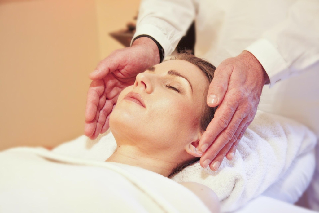 Photo of a Reiki therapist giving Reiki healing through the hands to the clients head