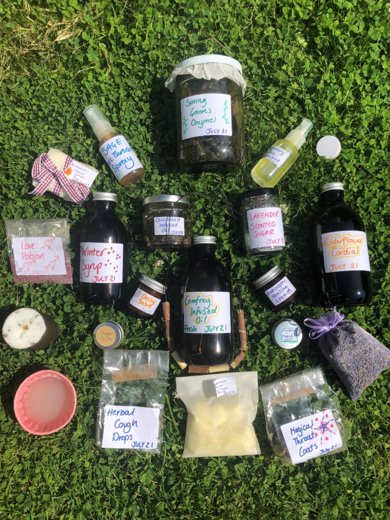A photo showing various home-made remedies made at the Junior Herbalist Club laid out on grass.